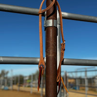 rough out double stitched single slide ear headstall with conchos hanging on fence