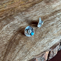 Pair of silver earrings with turquoise stones on a wooden surface