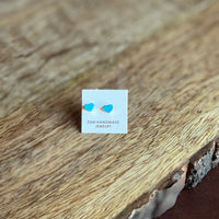 Pair of heart-shaped earrings on a 'Zuni Handmade Jewelry' card on a wooden surface.