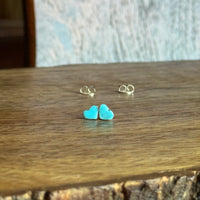 Turquoise heart-shaped earrings on a wooden surface