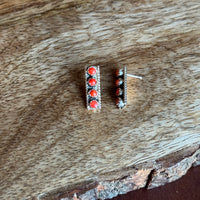 Pair of earrings with red stones on a wooden surface