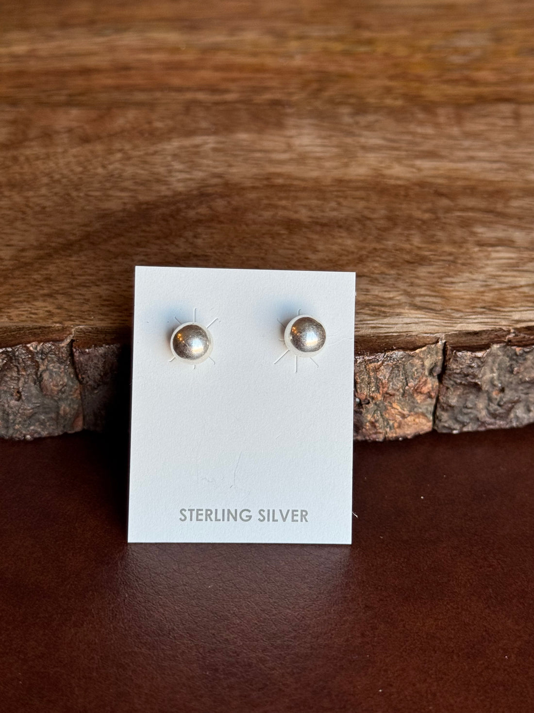 Pair of sterling silver earrings on a white card with wooden background
