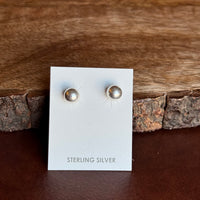 Pair of sterling silver earrings on a white card with wooden background