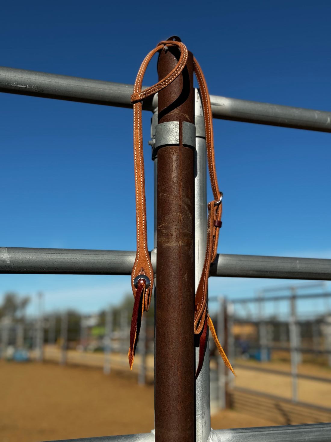 rough out double stitched single slide ear headstall with conchos hanging on fence