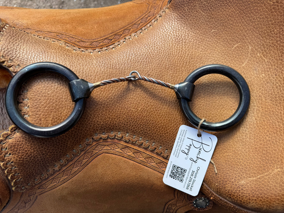 extra thick weighted ring snaffle with small copper twisted mouth laid across saddle