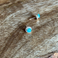 Pair of small turquoise gemstone earrings on a wooden surface