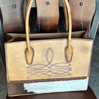 distressed light brown leather brief case with brown boot stitch design and hair on hide strip along bottom of bag, with leather whipstitching, and tall stand up handles