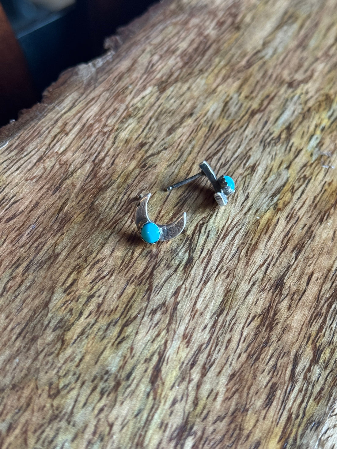Pair of earrings with turquoise stones on a wooden surface