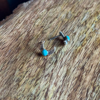 Pair of earrings with turquoise stones on a wooden surface