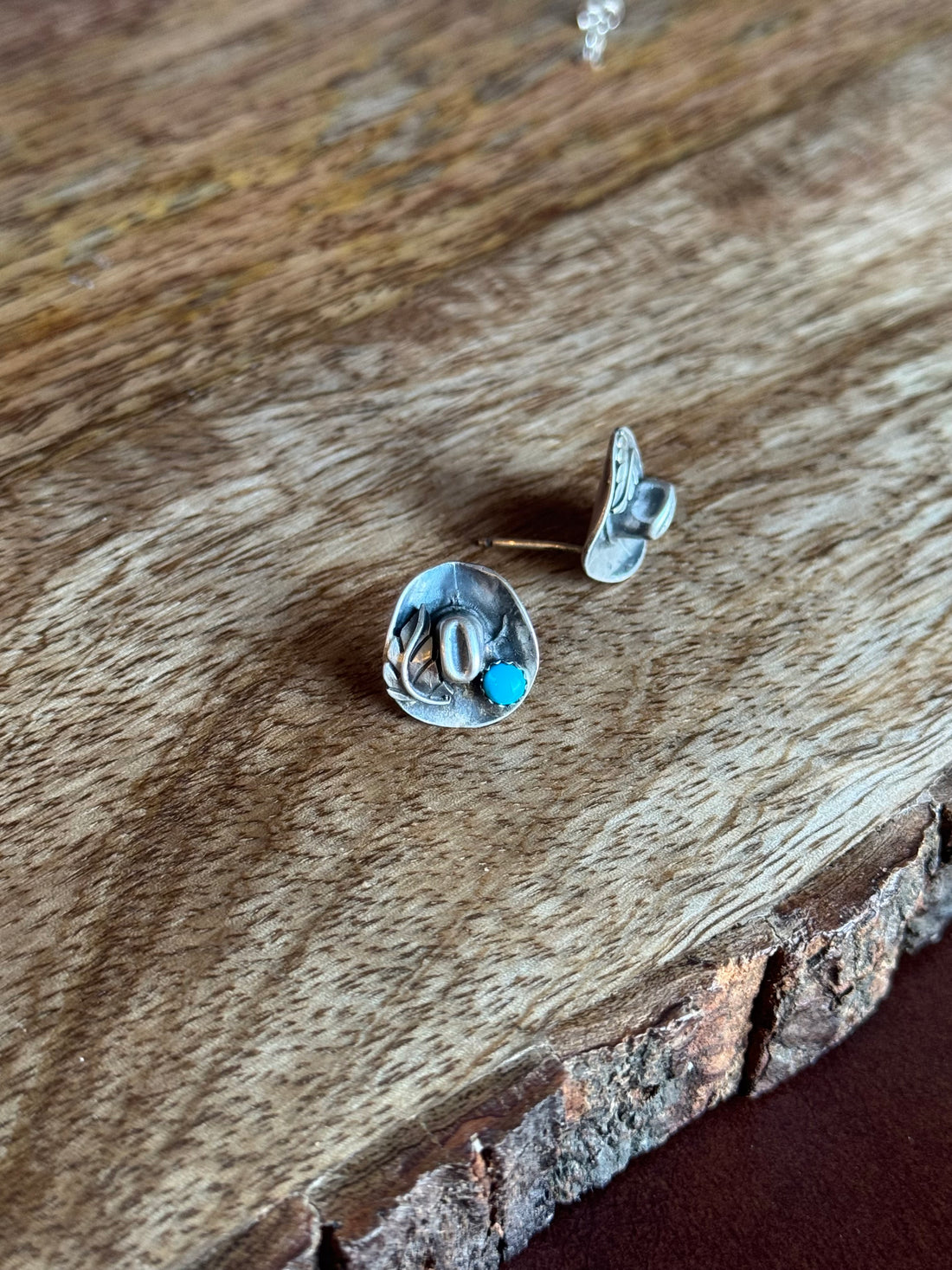 Pair of silver earrings with turquoise stones on a wooden surface