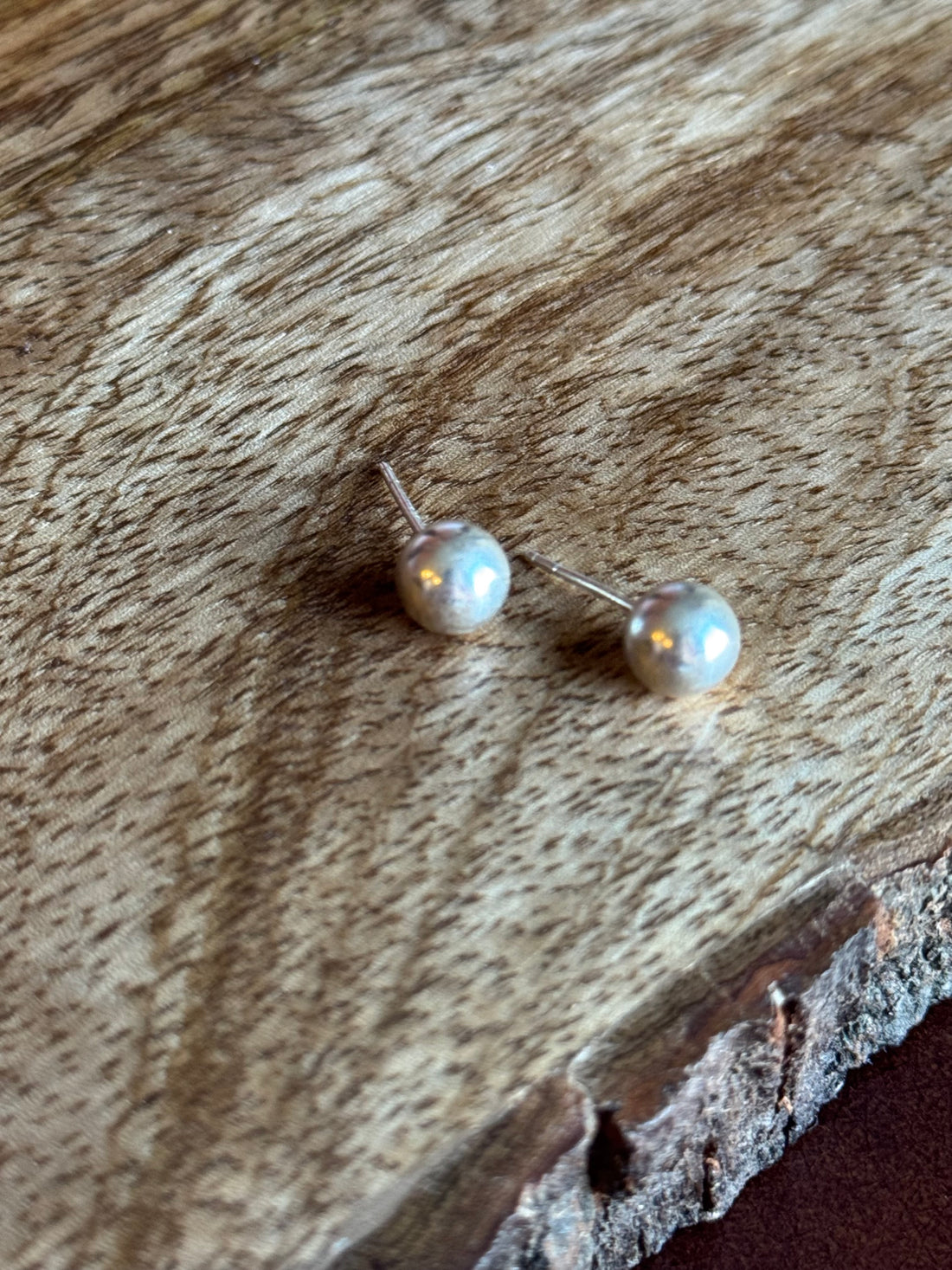 Pearl stud earrings on a wooden surface