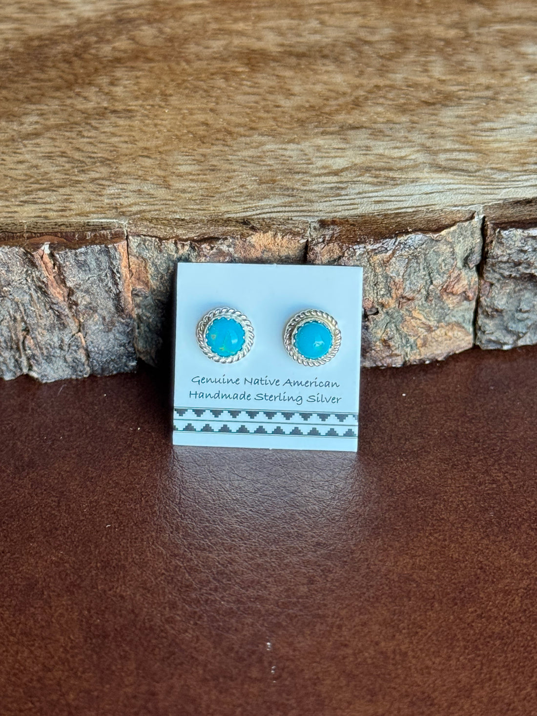 Pair of turquoise earrings on a card against a wooden background