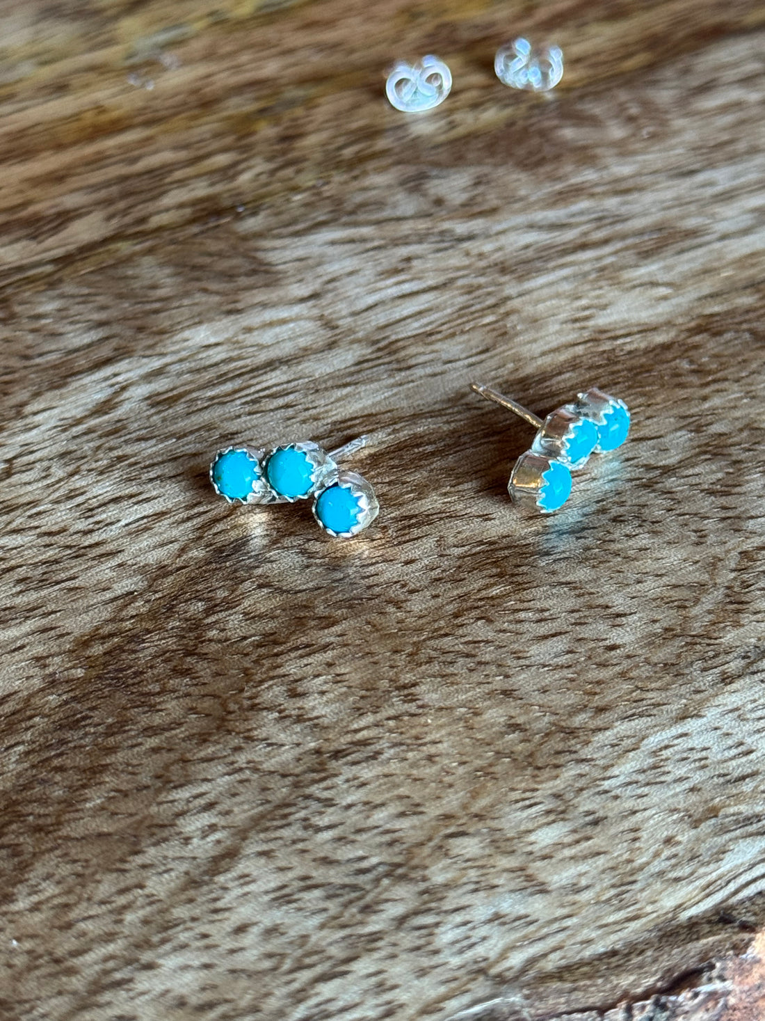 Turquoise stud earrings on a wooden surface