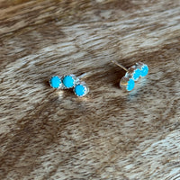Turquoise stud earrings on a wooden surface