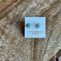 Pair of turquoise stud earrings on a Zuni Handmade Jewelry card, placed on a wooden surface.