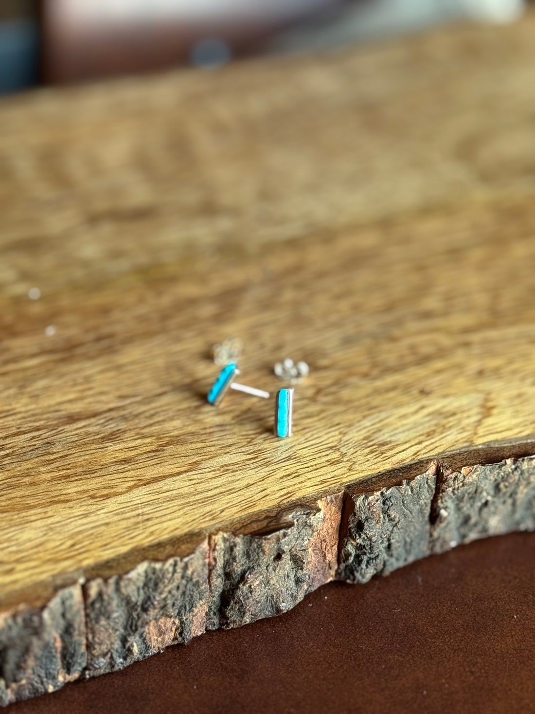 Small silver and turquoise earrings on a wooden surface