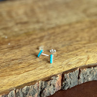 Small silver and turquoise earrings on a wooden surface