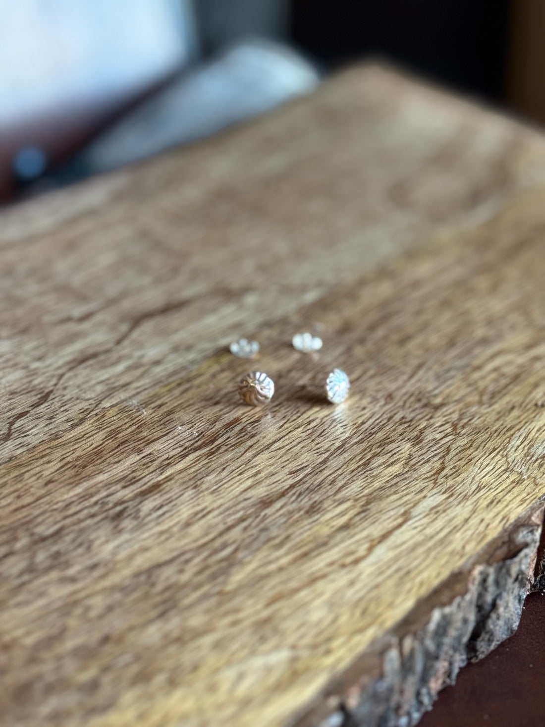 Small silver earrings on a wooden surface