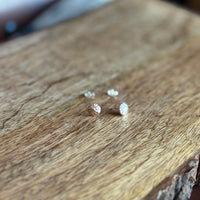 Small silver earrings on a wooden surface