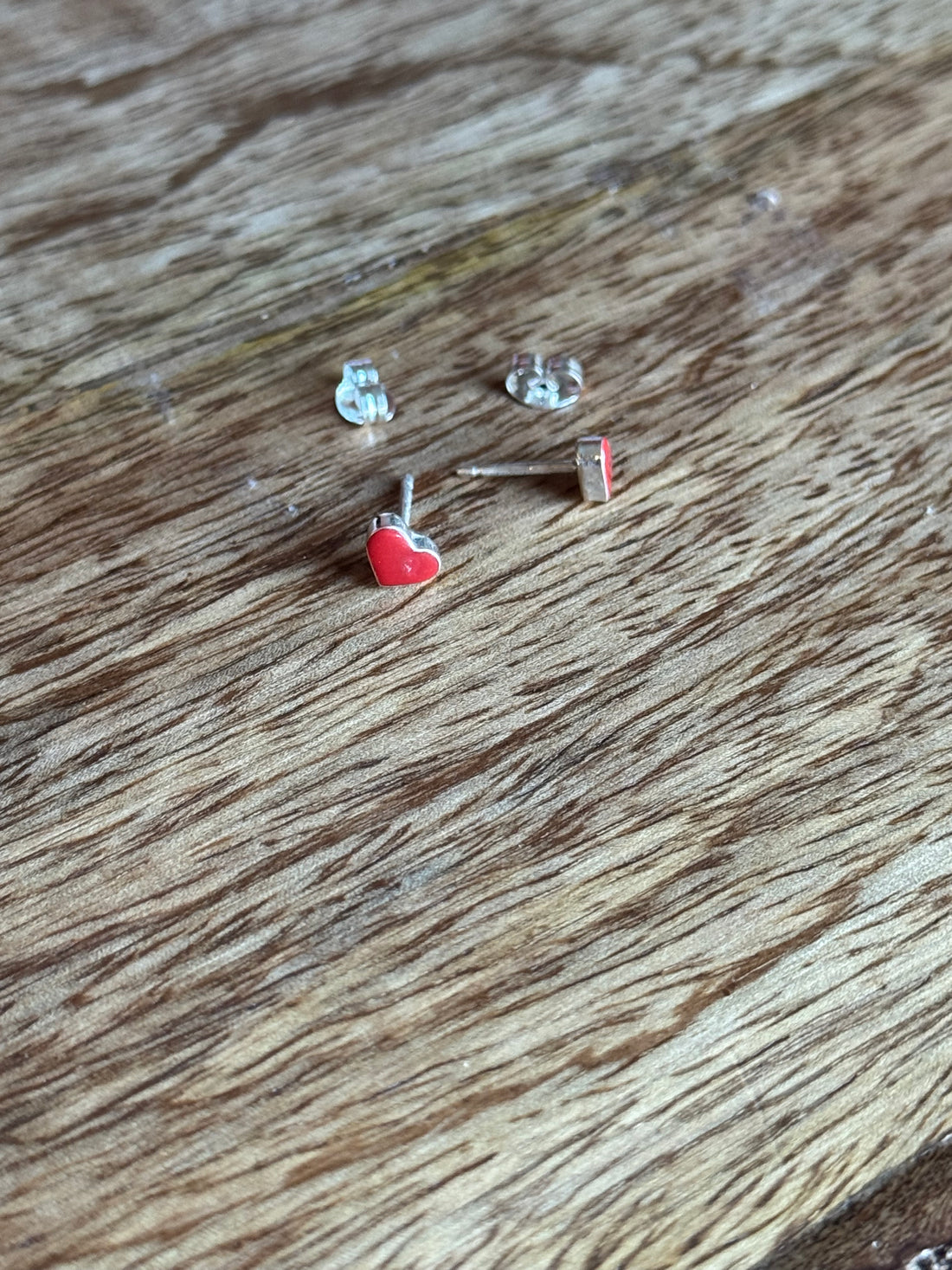 Small silver earring with red gemstone on a wooden surface