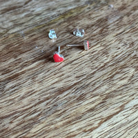 Small silver earring with red gemstone on a wooden surface