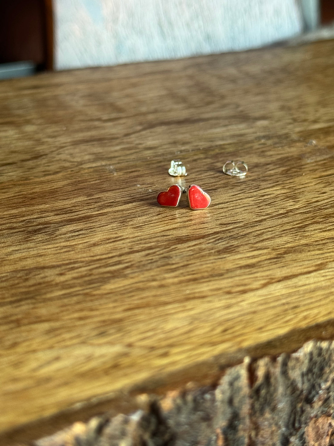 Red heart-shaped earrings on a wooden surface