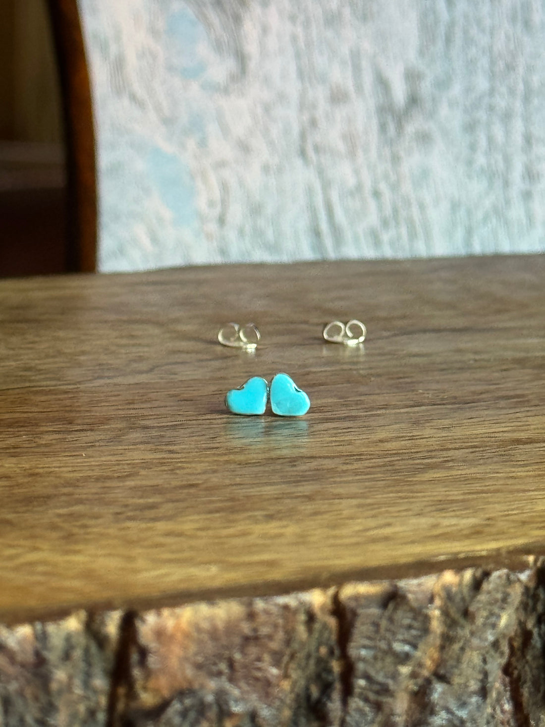 Turquoise heart-shaped earrings on a wooden surface