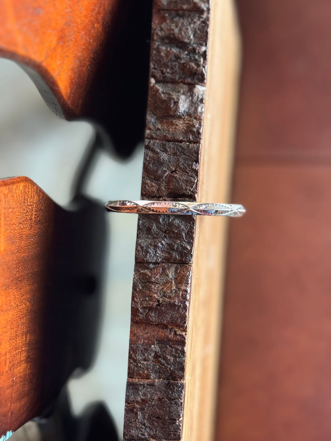 Close up of stamped silver bracelet on wooden surface
