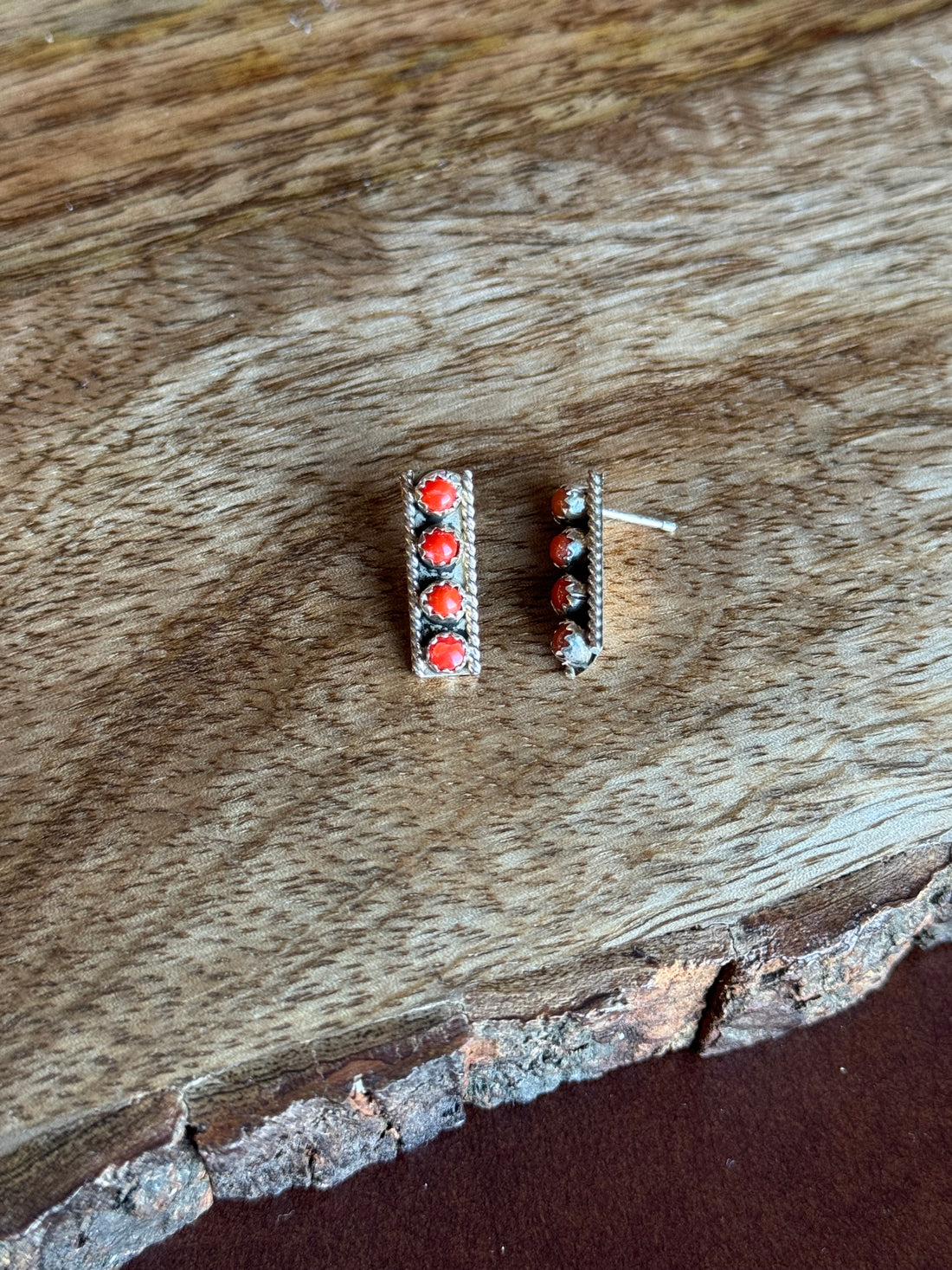 Pair of earrings with red stones on a wooden surface
