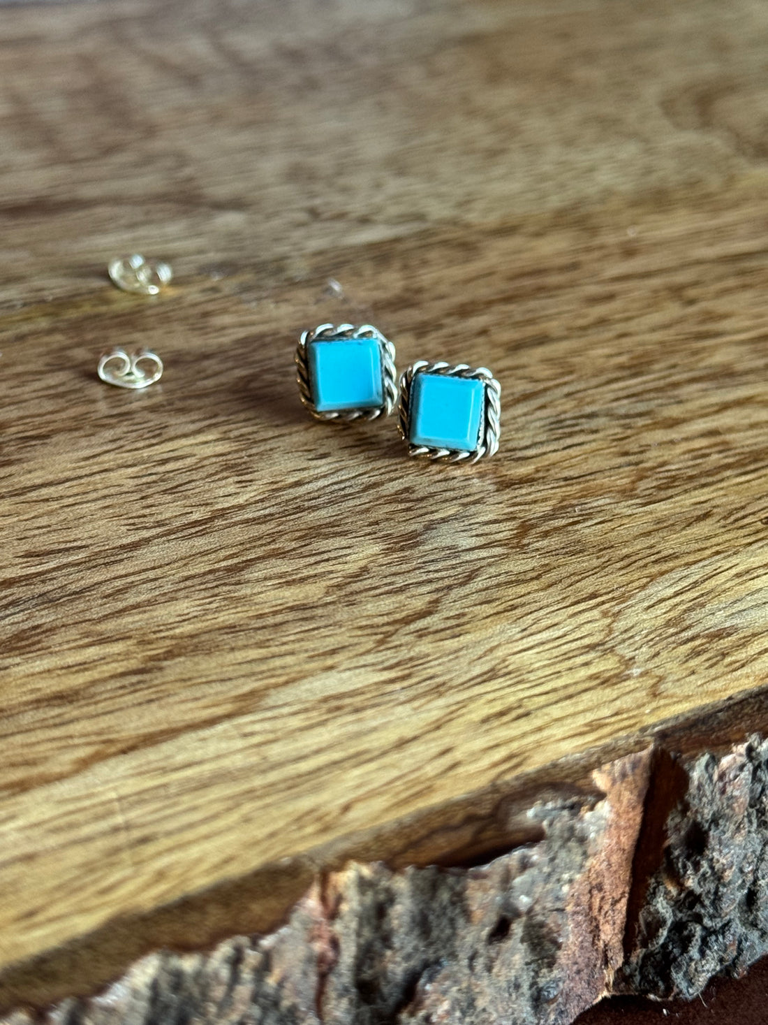 Turquoise square stud earrings on a wooden surface