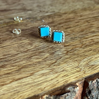 Turquoise square stud earrings on a wooden surface