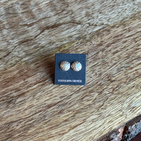 Pair of silver earrings on a black card with a wooden surface background