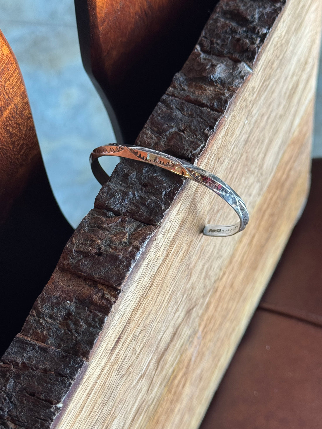 Stamped Silver bracelet on a wooden surface