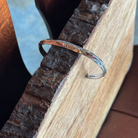 Stamped Silver bracelet on a wooden surface