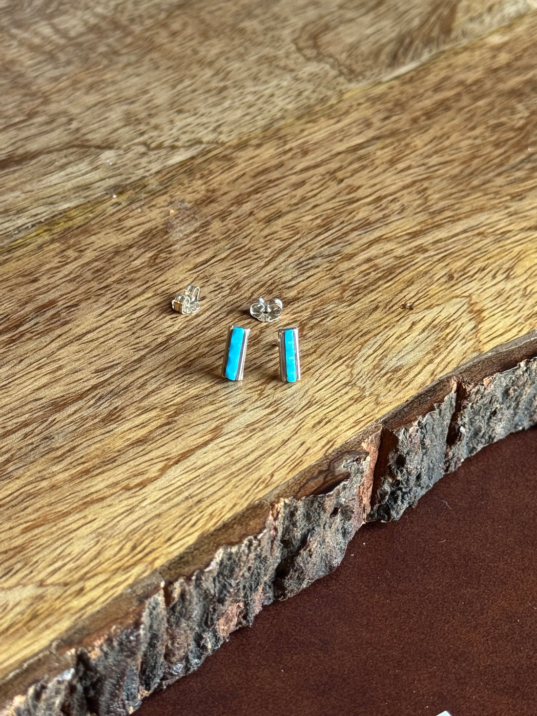 Small turquoise gemstone earrings on a wooden surface