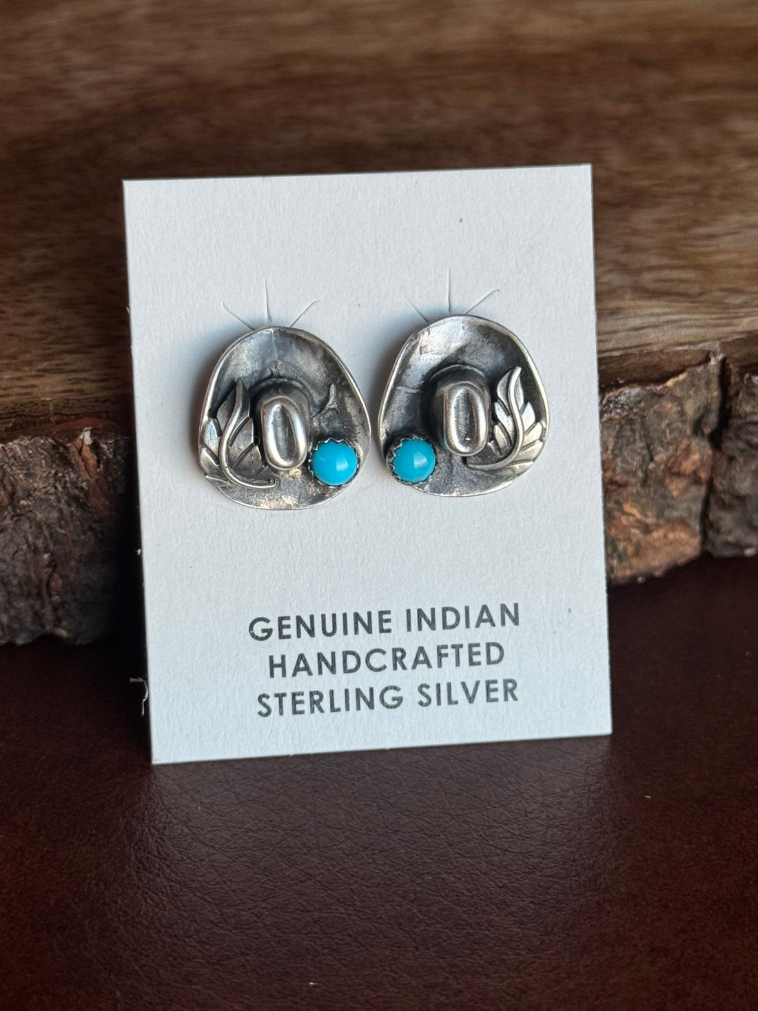 Pair of silver cowboy hat earrings with turquoise stones on a card labeled 'Genuine Indian Handcrafted Sterling Silver'.