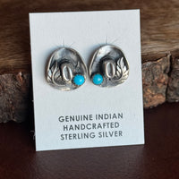 Pair of silver cowboy hat earrings with turquoise stones on a card labeled 'Genuine Indian Handcrafted Sterling Silver'.
