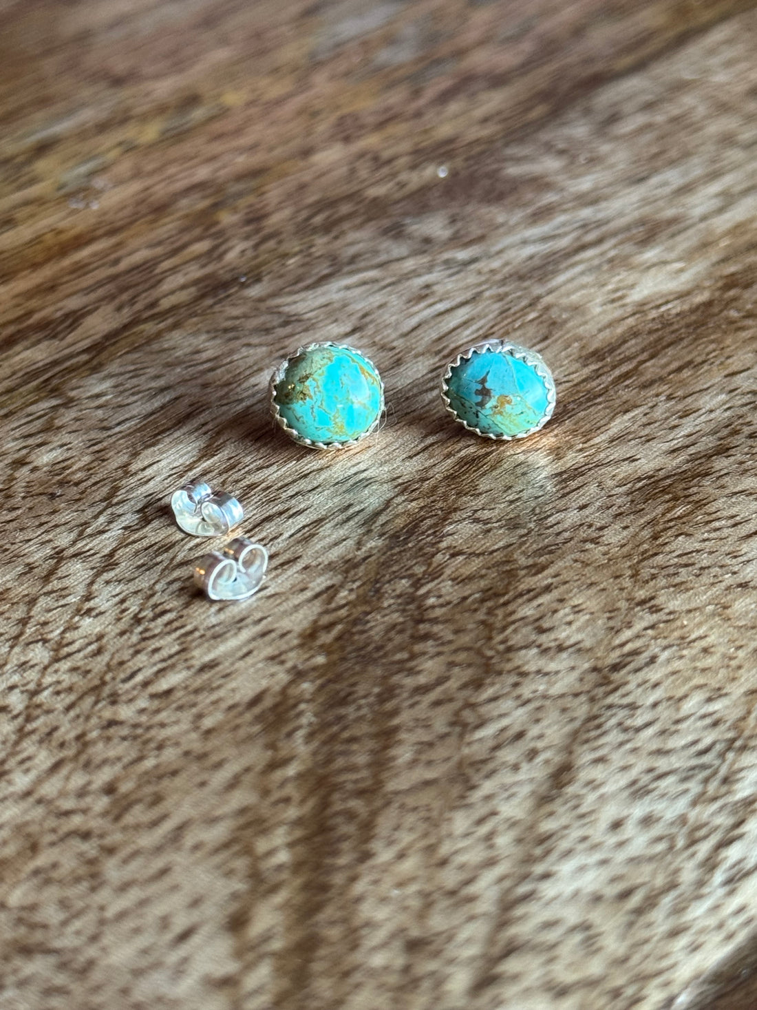 Turquoise stone earrings on a wooden surface