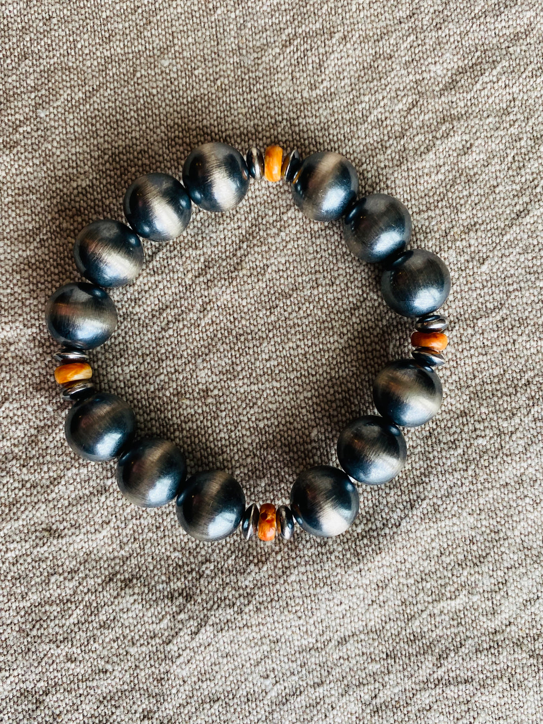 sterling silver ranch pearl stretchy bracelet  with orange beads on linen background